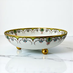 Antique Haviland Limoges France porcelain serving bowl with three gold spherical feet, ornate rim featuring floral and scroll motifs in blue, green, red, and gold; white base with maker’s marks “Haviland France” and “Haviland & Co Limoges”; very good vintage condition with one small factory flaw in center