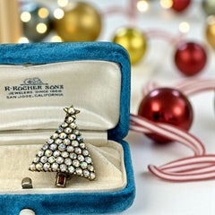 Vintage Hollycraft Christmas tree brooch with clear Aurora Borealis rhinestones in a gold-tone setting, featuring a gold star at the top and a red rhinestone base. Signed on the reverse and measuring approximately 1 3/8 inches tall by 1 inch wide.