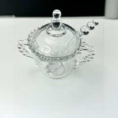 A vintage Imperial Candlewick pattern glass condiment jar set, featuring a handled jar, a fitted glass lid, and a matching glass spoon. Made between 1936 and 1984, the set is in excellent vintage condition and showcases the iconic bead design of the Candlewick collection.