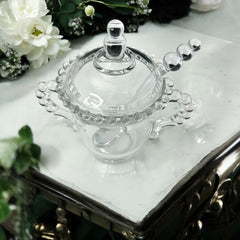 A vintage Imperial Candlewick pattern glass condiment jar set, featuring a handled jar, a fitted glass lid, and a matching glass spoon. Made between 1936 and 1984, the set is in excellent vintage condition and showcases the iconic bead design of the Candlewick collection.