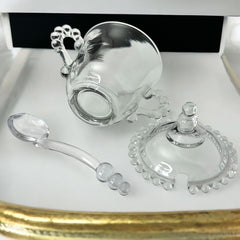 A vintage Imperial Candlewick pattern glass condiment jar set, featuring a handled jar, a fitted glass lid, and a matching glass spoon. Made between 1936 and 1984, the set is in excellent vintage condition and showcases the iconic bead design of the Candlewick collection.