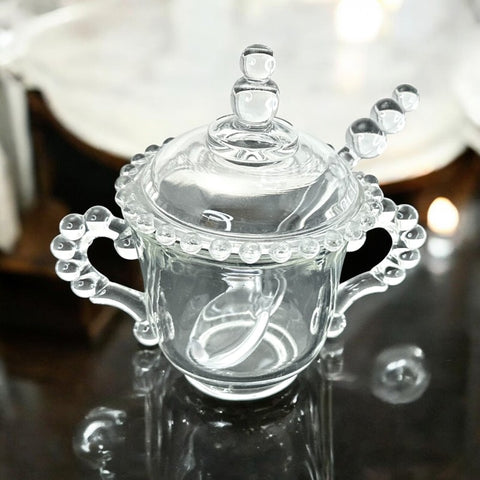 A vintage Imperial Candlewick pattern glass condiment jar set, featuring a handled jar, a fitted glass lid, and a matching glass spoon. Made between 1936 and 1984, the set is in excellent vintage condition and showcases the iconic bead design of the Candlewick collection.