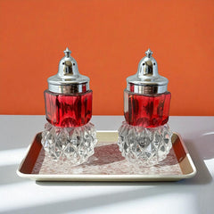Pair of vintage Indiana Glass salt and pepper shakers featuring clear diamond point bases, paneled ruby red flash bands, and chrome-plated screw-on lids marked Made in Hong Kong. Mid-century design in excellent vintage condition.