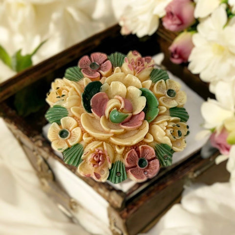Vintage 1950s Japan celluloid floral brooch featuring a cream-colored molded design with a central flower surrounded by smaller blooms, hand-painted in soft pink and green. Signed Japan on the back, in very good vintage condition.