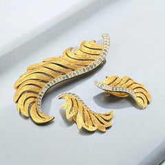 Vintage Jomaz feather brooch and earrings set from the early 1960s, featuring clear pave rhinestones set in silver-tone metal for the quill and textured gold-plated metal for the feather. Signed Jomaz on the back, in very good vintage condition with all original rhinestones present.