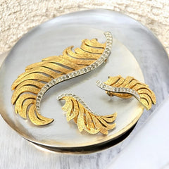 Vintage Jomaz feather brooch and earrings set from the early 1960s, featuring clear pave rhinestones set in silver-tone metal for the quill and textured gold-plated metal for the feather. Signed Jomaz on the back, in very good vintage condition with all original rhinestones present.