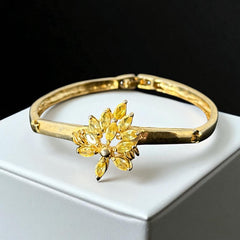 Vintage 1990s gold tone bracelet with curved links and a single jonquil marquise rhinestone flower centerpiece, elegant and gently worn.