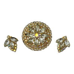 Verified Juliana #1402 vintage clear rhinestone and gold-tone floral brooch with matching clip-on earrings. The brooch features dimensional layered rings of clear chaton and AB rhinestones, with marquise rhinestones encircling the center. Earrings showcase a leaf-shaped design with marquise rhinestones and AB chaton accents. Mid-century elegance from the late 1950s or early 1960s.