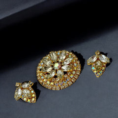 Verified Juliana #1402 vintage clear rhinestone and gold-tone floral brooch with matching clip-on earrings. The brooch features dimensional layered rings of clear chaton and AB rhinestones, with marquise rhinestones encircling the center. Earrings showcase a leaf-shaped design with marquise rhinestones and AB chaton accents. Mid-century elegance from the late 1950s or early 1960s.