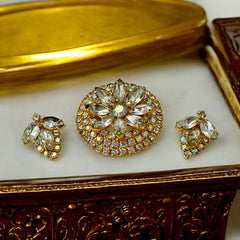 Verified Juliana #1402 vintage clear rhinestone and gold-tone floral brooch with matching clip-on earrings. The brooch features dimensional layered rings of clear chaton and AB rhinestones, with marquise rhinestones encircling the center. Earrings showcase a leaf-shaped design with marquise rhinestones and AB chaton accents. Mid-century elegance from the late 1950s or early 1960s.