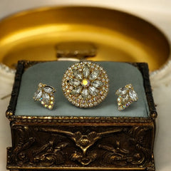 Verified Juliana #1402 vintage clear rhinestone and gold-tone floral brooch with matching clip-on earrings. The brooch features dimensional layered rings of clear chaton and AB rhinestones, with marquise rhinestones encircling the center. Earrings showcase a leaf-shaped design with marquise rhinestones and AB chaton accents. Mid-century elegance from the late 1950s or early 1960s.