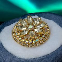 Verified Juliana #1402 vintage clear rhinestone and gold-tone floral brooch with matching clip-on earrings. The brooch features dimensional layered rings of clear chaton and AB rhinestones, with marquise rhinestones encircling the center. Earrings showcase a leaf-shaped design with marquise rhinestones and AB chaton accents. Mid-century elegance from the late 1950s or early 1960s.