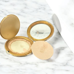 Vintage 1950s Kigu gold-tone powder compact with guilloché moiré lid, original puff, and mirror—collectible beauty accessory with timeless charm.