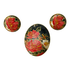 Hand-painted floral brooch and screw-back earrings set in lacquered wood with gold-tone trim, featuring red and pink flowers on a black background, signed by the artist.