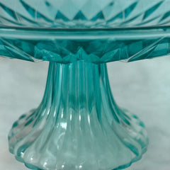 A vibrant aqua blue pressed glass footed dish with a diamond pattern, versatile for serving desserts, fruit, or candy, mid-century design.