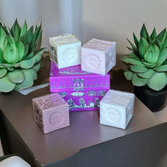 Fuchsia toile de Jouy gift box with intricate patterns, containing four artisanal Marseille cube soaps in Fig, Jasmine, Rose, and Lily of the Valley fragrances.