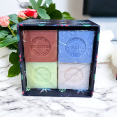 Gift box featuring a charming Moon and Sun design on a midnight blue background. Contains four artisanal Marseille cube soaps in Violet, Rose, Verbena, and Red Berries fragrances.