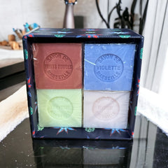 Gift box featuring a charming Moon and Sun design on a midnight blue background. Contains four artisanal Marseille cube soaps in Violet, Rose, Verbena, and Red Berries fragrances.