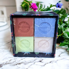 Gift box featuring a charming Moon and Sun design on a midnight blue background. Contains four artisanal Marseille cube soaps in Violet, Rose, Verbena, and Red Berries fragrances.