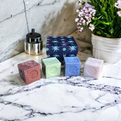 Gift box featuring a charming Moon and Sun design on a midnight blue background. Contains four artisanal Marseille cube soaps in Violet, Rose, Verbena, and Red Berries fragrances.