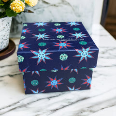 Gift box featuring a charming Moon and Sun design on a midnight blue background. Contains four artisanal Marseille cube soaps in Violet, Rose, Verbena, and Red Berries fragrances.