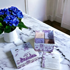 Purple Toile de Jouy gift box featuring intricate patterns, containing four artisanal Marseille cube soaps in Lilac, Lavender, Fig, and Rose fragrances.