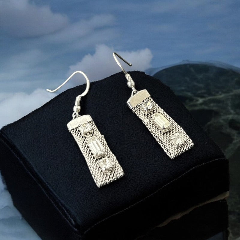 Vintage clear rhinestone and silver tone mesh dangle earrings with emerald-cut rhinestones and chaton accents, paired with sterling silver ear wires, photographed against a clean, neutral backdrop.
