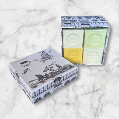 Gray Toile de Jouy gift box with intricate patterns, containing four artisanal Marseille cube soaps in Honeysuckle, Almond, Verbena, and Jasmine fragrances.