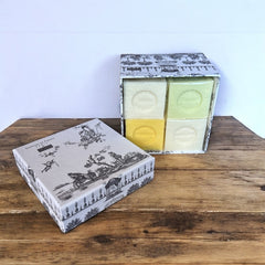 Gray Toile de Jouy gift box with intricate patterns, containing four artisanal Marseille cube soaps in Honeysuckle, Almond, Verbena, and Jasmine fragrances.