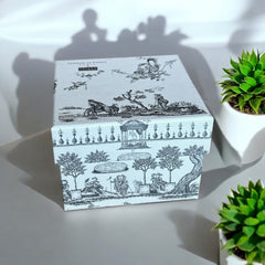 Gray Toile de Jouy gift box with intricate patterns, containing four artisanal Marseille cube soaps in Honeysuckle, Almond, Verbena, and Jasmine fragrances.