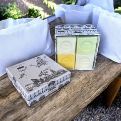 Gray Toile de Jouy gift box with intricate patterns, containing four artisanal Marseille cube soaps in Honeysuckle, Almond, Verbena, and Jasmine fragrances.