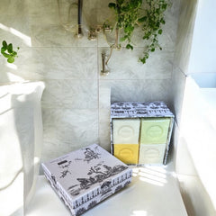 Gray Toile de Jouy gift box with intricate patterns, containing four artisanal Marseille cube soaps in Honeysuckle, Almond, Verbena, and Jasmine fragrances.