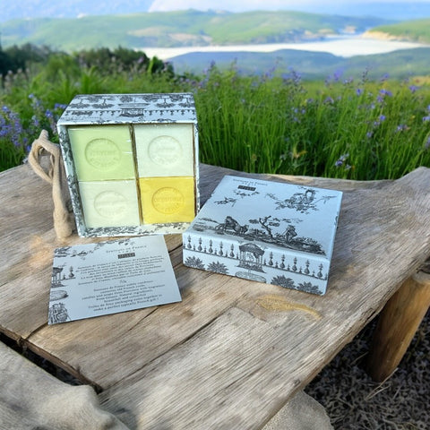 Gray Toile de Jouy gift box with intricate patterns, containing four artisanal Marseille cube soaps in Honeysuckle, Almond, Verbena, and Jasmine fragrances.