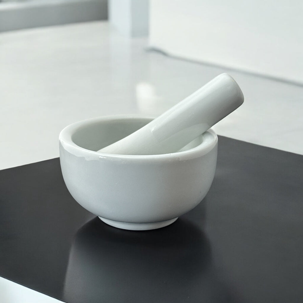 Elegant white porcelain mortar and pestle with glazed exterior and raw interior, designed for tabletop spice grinding and culinary rituals.