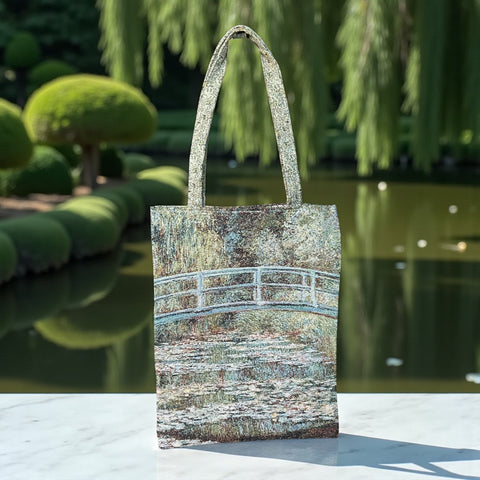 Tapestry tote bag featuring Monet’s Japanese Bridge and Water Lilies, woven in France with soft green, blue, and pink tones; double-sided print with long handles, inspired by Impressionist art.