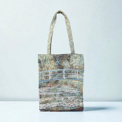 Tapestry tote bag featuring Monet’s Japanese Bridge and Water Lilies, woven in France with soft green, blue, and pink tones; double-sided print with long handles, inspired by Impressionist art.