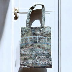 Tapestry tote bag featuring Monet’s Japanese Bridge and Water Lilies, woven in France with soft green, blue, and pink tones; double-sided print with long handles, inspired by Impressionist art.