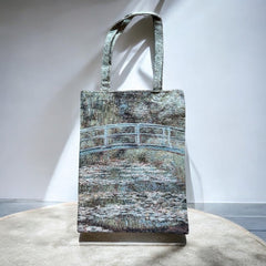 Tapestry tote bag featuring Monet’s Japanese Bridge and Water Lilies, woven in France with soft green, blue, and pink tones; double-sided print with long handles, inspired by Impressionist art.