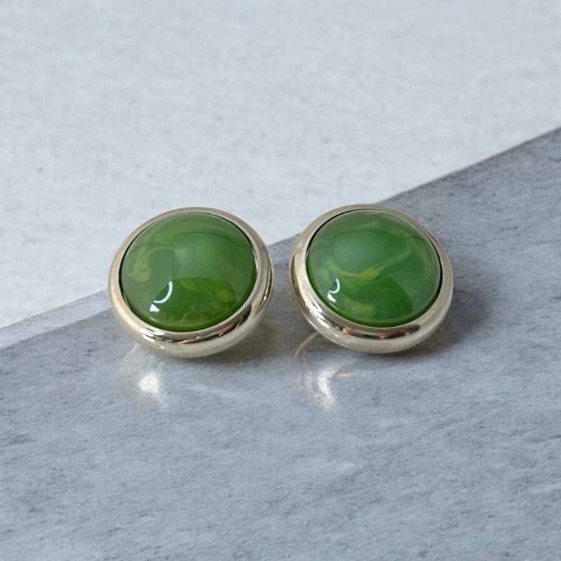 Vintage French button earrings featuring moss green marbled plastic cabochons set in silver tone borders. A classy and elegant 1970s design with retro charm, perfect for sustainable and eco-conscious fashion lovers.