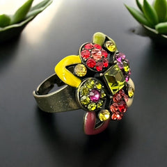 Adjustable brass ring with multicolor enamel leaves and rhinestone floral motifs, featuring vibrant hues of red, pink, green, purple, moss green, cream, and yellow, in very good second-hand condition.