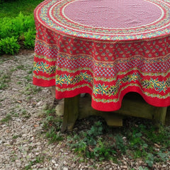 Round Provence-style cotton tablecloth by Le Cluny, featuring a vibrant red background with yellow mimosa and black olive detailing. Measures 70 inches in diameter, made in France, suitable for indoor and outdoor use, and machine washable for easy care.