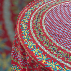Round Provence-style cotton tablecloth by Le Cluny, featuring a vibrant red background with yellow mimosa and black olive detailing. Measures 70 inches in diameter, made in France, suitable for indoor and outdoor use, and machine washable for easy care.