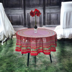 Round Provence-style cotton tablecloth by Le Cluny, featuring a vibrant red background with yellow mimosa and black olive detailing. Measures 70 inches in diameter, made in France, suitable for indoor and outdoor use, and machine washable for easy care.