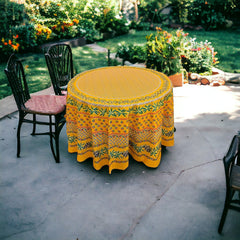 Round Provence-style cotton tablecloth by Le Cluny, featuring a vibrant yellow background with detailed mimosa and black olive patterns. Measures 70 inches in diameter, made in France, suitable for indoor and outdoor use, and machine washable for easy care.