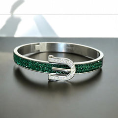 Emerald and clear rhinestone hinged bangle bracelet made of polished stainless steel with a modern belt buckle design, featuring sparkling accents and marked 316L S.Steel, photographed in excellent condition.