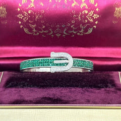 Emerald and clear rhinestone hinged bangle bracelet made of polished stainless steel with a modern belt buckle design, featuring sparkling accents and marked 316L S.Steel, photographed in excellent condition.