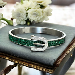 Emerald and clear rhinestone hinged bangle bracelet made of polished stainless steel with a modern belt buckle design, featuring sparkling accents and marked 316L S.Steel, photographed in excellent condition.