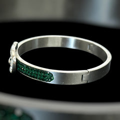Emerald and clear rhinestone hinged bangle bracelet made of polished stainless steel with a modern belt buckle design, featuring sparkling accents and marked 316L S.Steel, photographed in excellent condition.
