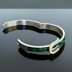 Emerald and clear rhinestone hinged bangle bracelet made of polished stainless steel with a modern belt buckle design, featuring sparkling accents and marked 316L S.Steel, photographed in excellent condition.