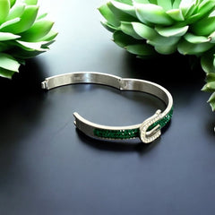 Emerald and clear rhinestone hinged bangle bracelet made of polished stainless steel with a modern belt buckle design, featuring sparkling accents and marked 316L S.Steel, photographed in excellent condition.